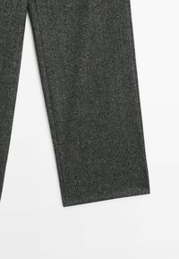 Jambes de pantalon en tissu de laine gris foncé avec un motif texturé subtil sur fond blanc.