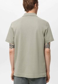 Kaki kortärmad polo-skjorta i ett texturerat tyg med klassisk krage. Enkel design, rak skärning och ren finish vid fållen.