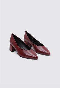 escarpins en cuir bordeaux avec un bout pointu et un talon block, présentant une texture lisse et des éléments de design minimalistes.