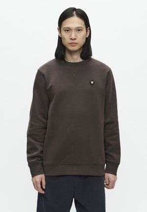 Brown sweatshirt in soft cotton blend, featuring a crew neck, long sleeves, and a small black logo on the chest. Textured fabric.