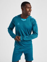 Teal atletisk trøje og shorts sæt lavet af blødt stof. Har lange ærmer, en rund halsudskæring og lyseblå detaljer på skuldrene.