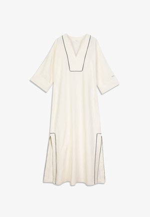 Vestido de lino en color blanco roto con ribete negro, que presenta un escote en V, mangas tres cuartos y aberturas laterales para facilitar el movimiento.