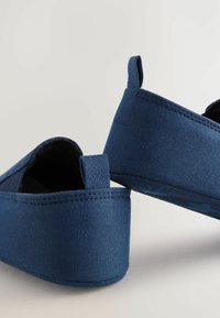 Bottines en tissu bleu à enfiler, présentant une texture lisse, une forme arrondie et de petites boucles en tissu au niveau du talon pour un enfilage facile.