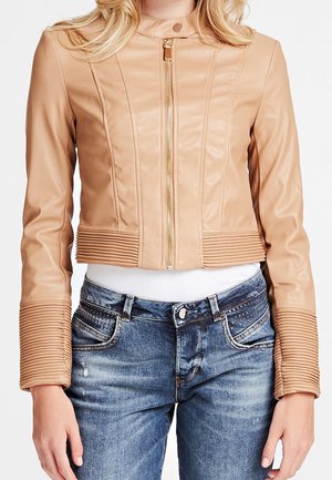 Damen kurz geschnittene beige Lederjacke mit Reißverschluss vorne und gerippten Details an Bündchen und Saum, kombiniert mit blauen Denim-Jeans.