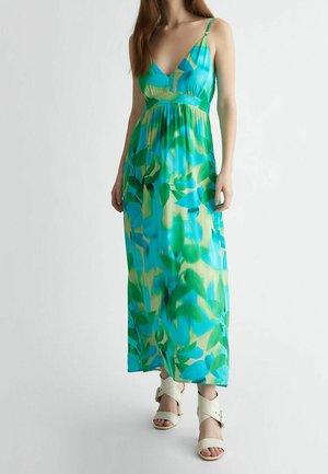 Vestido maxi de estampado floral en azul y verde, confeccionado en tela ligera, con escote en V y tirantes finos ajustables. Combinado con sandalias blancas.