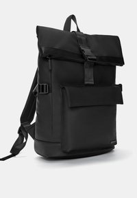 Czarny plecak wykonany z wytrzymałego materiału, z zamknięciem na rolowanie, regulowanymi paskami, przednią kieszenią oraz eleganckim, minimalistycznym designem.