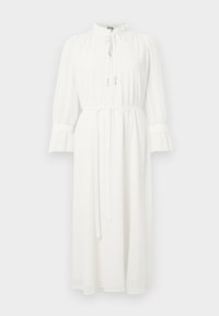 Bílé dlouhé šaty s dlouhým rukávem, vysokým výstřihem a detailem zavazování. Mají volánové manžety a pás v pase, vyrobené z lehké, splývavé látky.