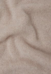 Helles rosa gestricktes Material mit einer sanften Textur. Der Stoff weist ein feines, gleichmäßiges Strickmuster auf, das zarte Wellen und Falten erzeugt.