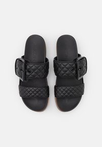 Czarne sandały z pikowaną cholewką i dużą klamrą. Gładka faktura i płaska podeszwa. Oznaczone nazwą marki "Marc Cain" na wkładce.