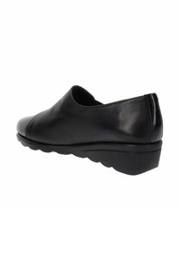 Scarpa nera in pelle slip-on con punta arrotondata, superficie liscia, tacco leggero e suola sagomata con un design ondulato.