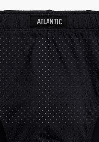 Czarna tkanina krótkich spodenek w białe kropki, elastyczny pas z oznaczeniem "ATLANTIC", gładka tekstura i dopasowany krój.