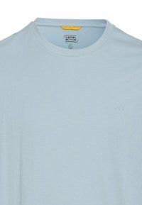Lys blå kortærmet T-shirt lavet af blødt stof, med en rund halsudskæring og et diskret logo på brystet. Etiketten viser størrelse 'L'.