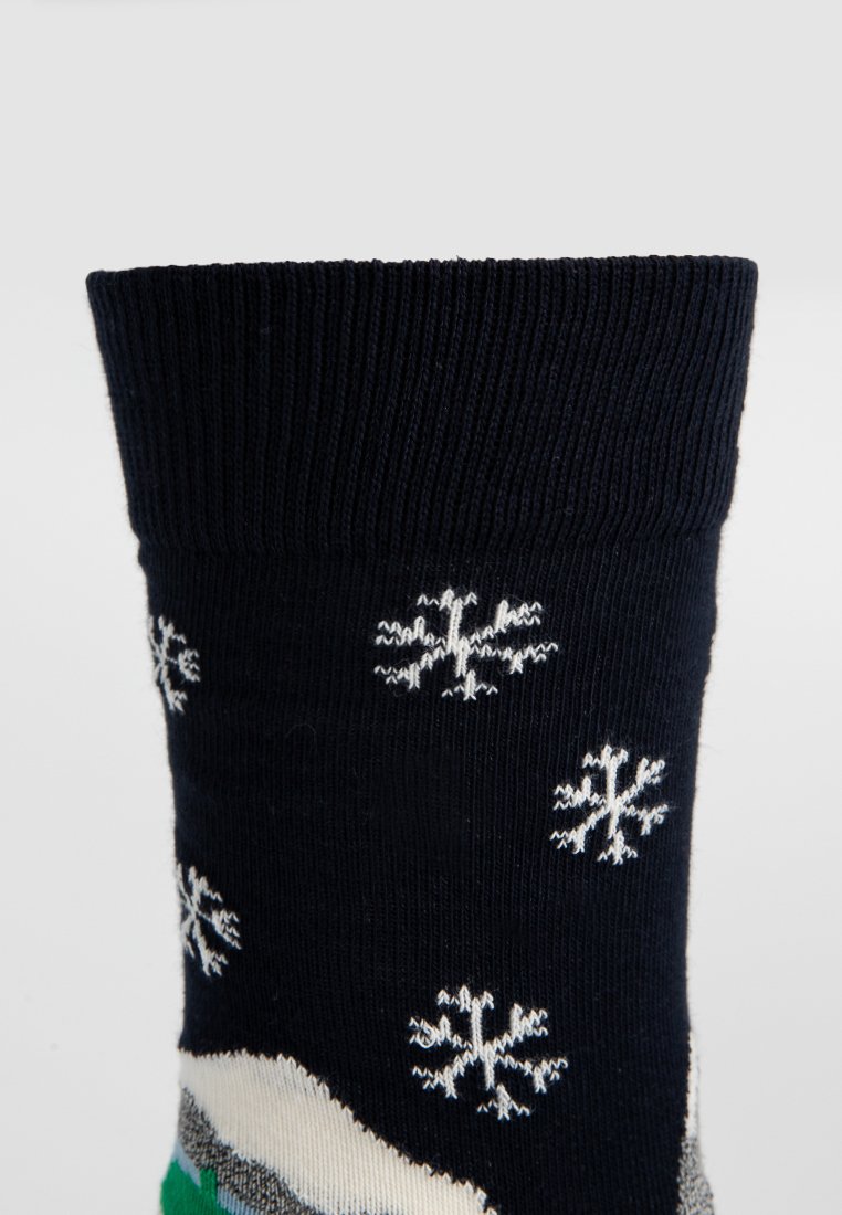 Navy Socken mit geripptem Bündchen, die weiße Schneeflockenmuster und ein grünes Bergdesign in der Nähe der Zehen zeigen. Hergestellt aus einem weichen, strukturierten Stoff.