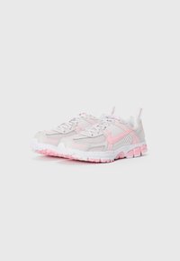 Une paire de chaussures de course Nike blanches et rose clair avec un tissu en maille et des semelles en caoutchouc, présentée côte à côte sur un fond uni.