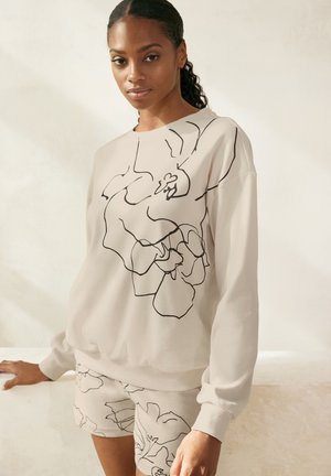 Helle beigefarbene Sweatshirt mit schwarzem floralem Liniendesign, Rundhalsausschnitt und Rippbündchen. Kombiniert mit passenden Shorts im gleichen Design.
