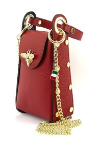Rode leren handtas met een voorflap met een bij-embleem, gouden hardware, een kettingband en decoratieve gouden studs aan de zijkant.