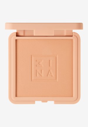 Pressat puderkompakt i ljus persika. Slät textur, har präglad logotyp, fyrkantig form och ett säkert flip-top lock.