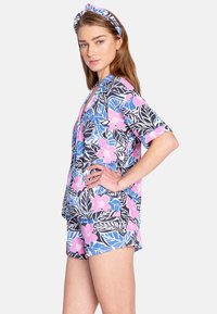 Blommönstrad kortärmad skjorta och shorts-set i blått, rosa och svart. Har en lös passform och en matchande hårband med liknande mönster.