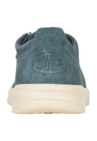 Baskets en daim bleu foncé avec un bout rond, des ouvertures élastiques et une semelle en caoutchouc crème. Présente un logo en relief à l'arrière.