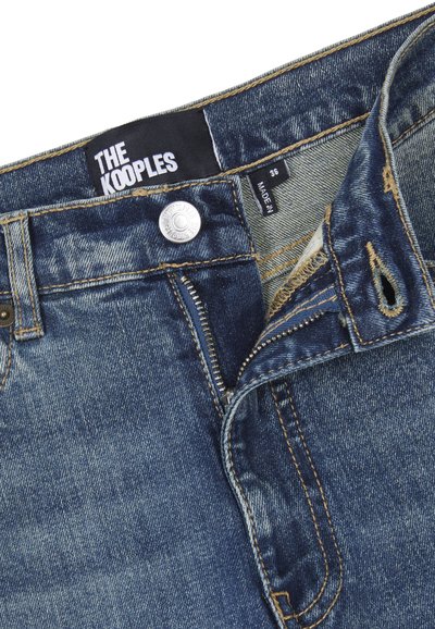 Jeans in denim di un blu medio, con un bottone argentato, chiusura lampo e cuciture beige. L'etichetta recita "THE KOOPLES", taglia 36.