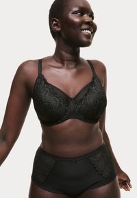 Set di lingerie nera composto da un reggiseno con coppa liscia rifinita in pizzo e slip a vita alta coordinati con dettagli texturizzati e fiocchetto.