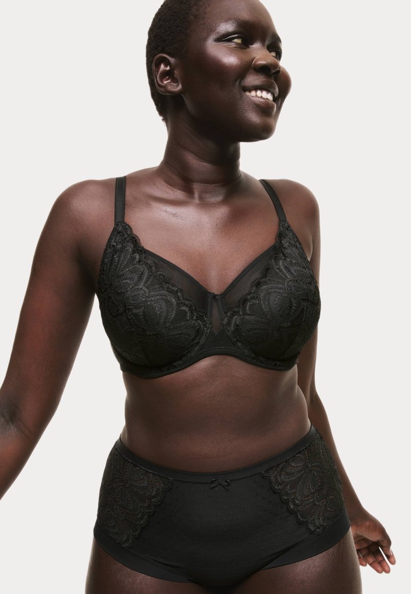 Set di lingerie nera composto da un reggiseno con coppa liscia rifinita in pizzo e slip a vita alta coordinati con dettagli texturizzati e fiocchetto.