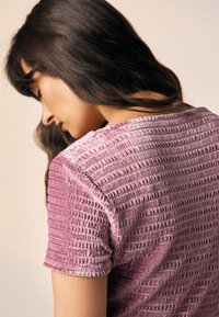 Korte mouwen shirt van textuurrijk roze stof met horizontale ribbels, voorzien van een ronde hals en zacht gerolde mouwen.