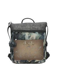 Sac à dos en tissu gris et à motifs, poche avant marron, couture décorative, logo en métal "Anekke" et texte "Tu es fait de magie" sur le rabat supérieur.