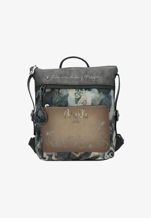 Rucksack mit grauem und gemustertem Stoff, braunem Frontfach, dekorativen Nähten, "Anekke" Metall-Logo und dem Text "Du bist aus Magie gemacht" auf der oberen Klappe.