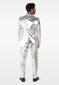 Silver metallic suit with a fitted design, featuring a single-breasted jacket and tapered trousers. Smooth texture with a shiny finish.