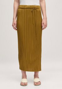 Gelaagde maxi rok in mosterdgeel met een elastische tailleband en een aantrekkoord detail. De stof heeft een soepele en vloeiende textuur.