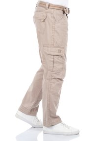 Beige Cargo-Hosen aus Baumwollmischung mit Seitentaschen, entspanntem Schnitt und genähtem Design. Kombiniert mit weißen Sneakers.