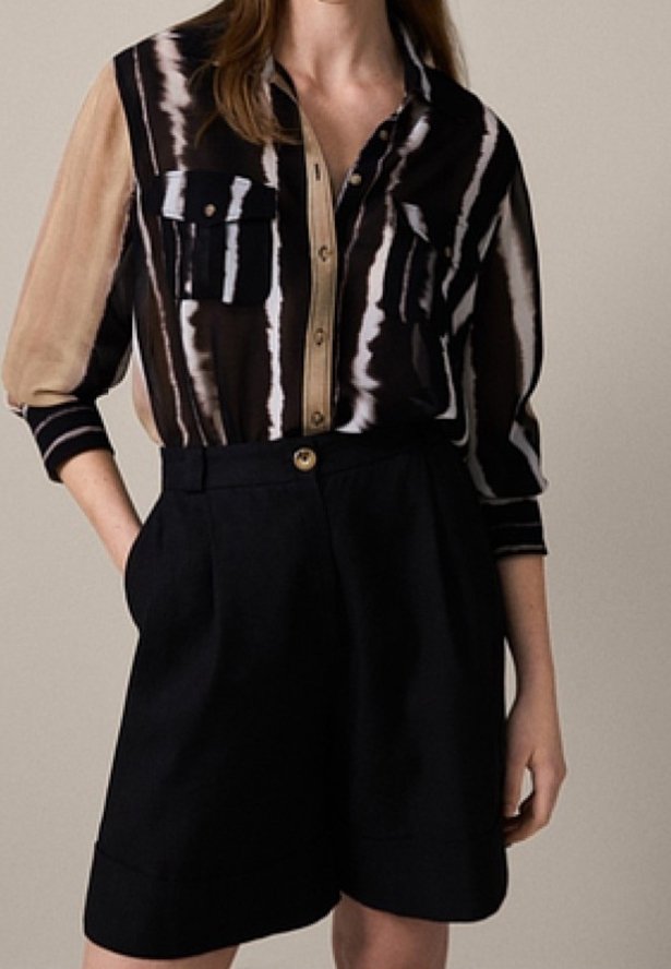 Skjorte med knapper foran med sorte og beige striber, to brystlommer; kombineret med højtaljede sorte shorts med en guldknap og plisseringer.