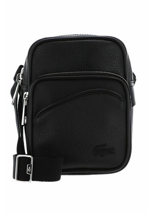 Petit sac bandoulière en cuir noir texturé avec poche zippée à l'avant, sangle ajustable en tissu et logo embossé dans le coin inférieur droit.