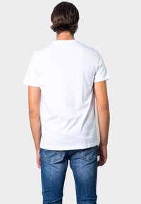 Hvit bomull T-skjorte med kort erm, rund hals og glatt tekstur, kombinert med blå denimjeans med baklommer.