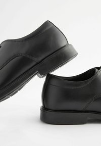 Chaussures en cuir noir avec une texture lisse, bout rond et semelle en caoutchouc basse. Présentent des coutures discrètes et un design classique.
