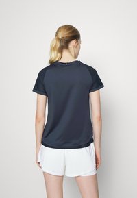 Černé sportovní tričko s krátkými rukávy a síťovinou na ramenou, kombinované s bílými šortkami. Hladký materiál s volným střihem.