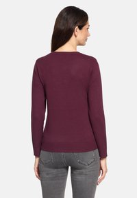 Bordeauxrode trui met lange mouwen, getailleerde pasvorm, geribde zoom en manchetten, gemaakt van een zacht gebreid materiaal. Achteraanzicht weergegeven.