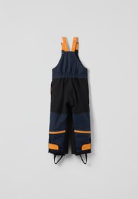 Kinder sneeuwbroeken in marineblauw en zwart met oranje reflecterende banden en verstevigde knieën en enkels, geïsoleerd op een grijze achtergrond.