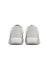 Witte sportschoenen met een texturepatroon aan de achterkant, zachte bovenkant van stof en een contrasterende grijze rubberen zool.