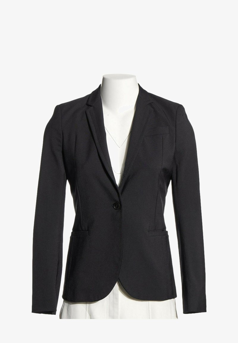 Blazer noir ajusté à bouton unique avec des revers crantés, présenté sur un mannequin blanc sans tête.