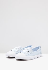 Jasnoniebieskie płócienne sneakersy z białym gumowym czubkiem i podeszwą. Posiadają sznurowaną konstrukcję oraz teksturowane panele materiałowe zapewniające wentylację.