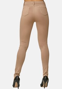 Nude skinny jeans med en slät textur, som har hög midja, två bakfickor och en åtsittande design, i kombination med svarta högklackade skor.