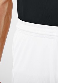 Leichte weiße Sportshorts mit einem elastischen Bund, die dezente Texturdetails und eine glatte Stoffoberfläche aufweisen.