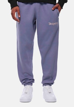 Lavender sweatpants with ribbed cuffs and side pockets. Embroidered "Dropsize" logo on the left thigh. Paired with white sneakers.