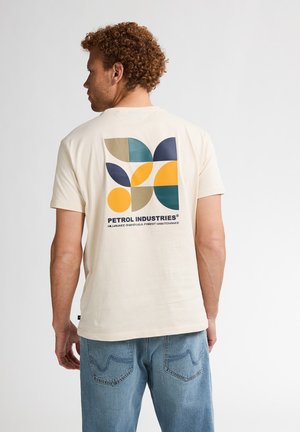 T-shirt en coton beige avec un graphisme géométrique coloré au dos, comportant des formes circulaires et des feuilles, ainsi que le logo "Petrol Industries".