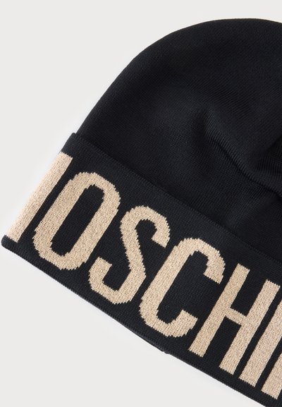 Bonnet en maille noire avec large revers plié présentant de grandes lettres beiges épelant partiellement un nom de marque.