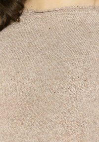Maglione in maglia color beige chiaro con una superficie testurizzata e una leggera lucentezza, caratterizzato da un colletto rotondo e maniche corte e morbide.