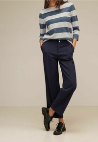 Långärmad, blårandig topp som matchas med navy högmidjade byxor. Byxorna har smalnande ben och framfickor, kompletterat med svarta snörskor.