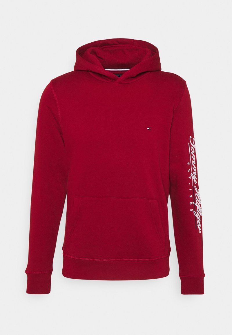 Sweat à capuche rouge avec poche avant, petit logo sur la poitrine et texte blanc « Tommy Hilfiger EST. 1985 » sur la manche droite.